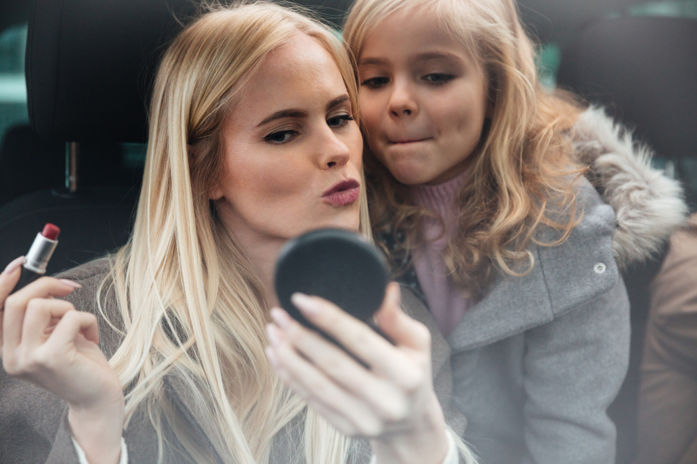 Mother sharing makeup and lipstick with daughter