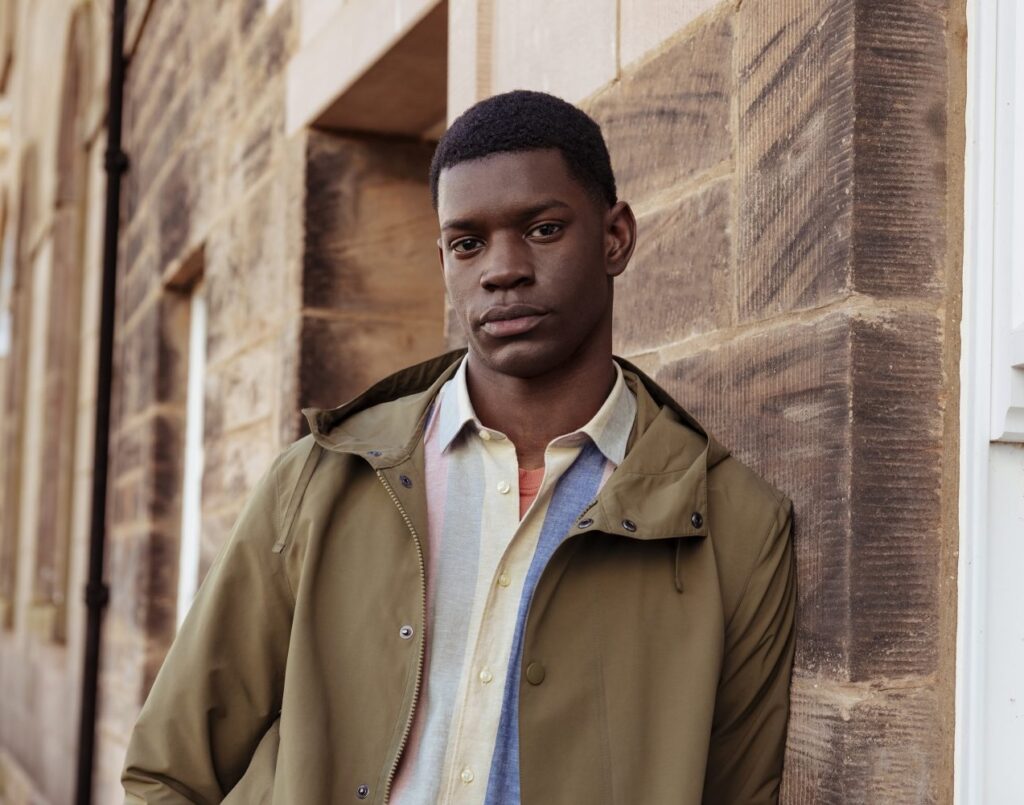 Man leaning against a wall wearing Barbour Quay Showerproof Jacket